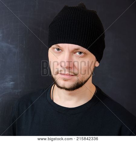 self-reliant bearded attractive man in black with a confident look on the background of a school board. square view.