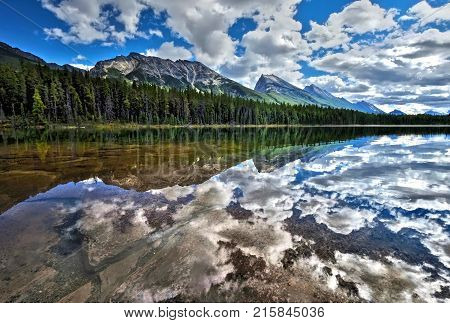 Honeymoon lake surronded by forest and mountains. Beautiful reflections in crystal clear water of Endless Chain Ridge in Canadian Rockies. Jasper National Park. Alberta. Canada.