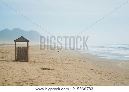 Wild Abandoned Unexplored Beach With A Lonely Wooden Wicker Construction, Bright Blue Turquoise Sea
