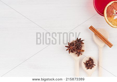 Christmas drink - ingredients for mulled wine. Red wine and wood spoons with anise stars cinnamon dried oranges on wood white board.