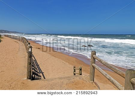 Wooden Pole Barrier On Beachfront Against Coastal  Landscape
