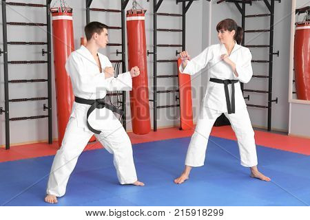 Young man and woman practicing karate in dojo