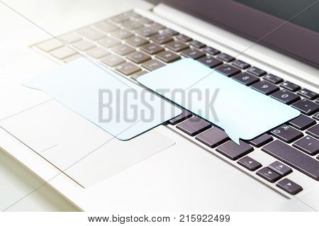 Online communication chatting on social media or commenting on an internet forum concept. Company reputation or review. Two blank speech bubbles on laptop keyboard.