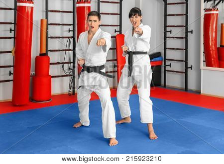 Young man and woman practicing karate in dojo