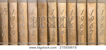 Old gold year books from 1958 to 1968 on shelf showing spine