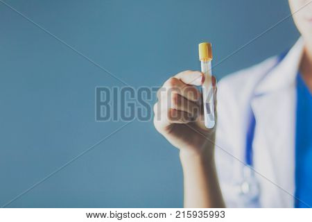 Female medical or research scientist or doctor using looking at a test tube of clear solution in a lab or laboratory