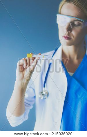 Female medical or research scientist or doctor using looking at a test tube of clear solution in a lab or laboratory
