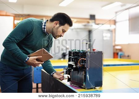 Young handsome student of mechatronics working on project