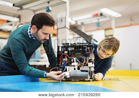 Young attractive students of mechatronics working on project together
