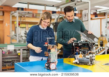 Young attractive students of mechatronics working on project together