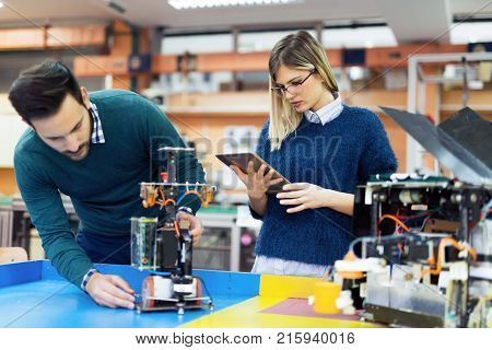 Young attractive students of mechatronics working on project together