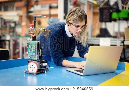 Young attractive woman engineer working on robotics project using laptop