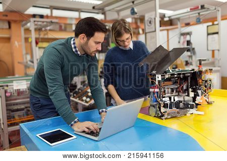 Young attractive students of mechatronics working on project together