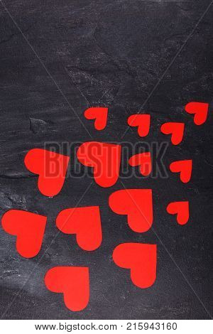Red hearts of different sizes go from a smaller to a larger diagonal to the left down on a stone background