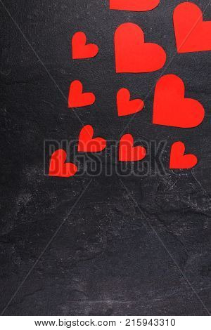 Red hearts of different sizes go from a smaller to a larger diagonal to the right up against a stone background