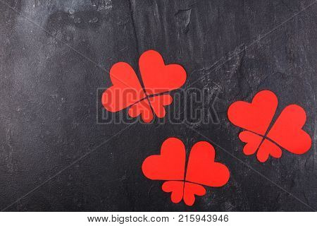Red hearts carved in different sizes lined up in butterflies on a stone background