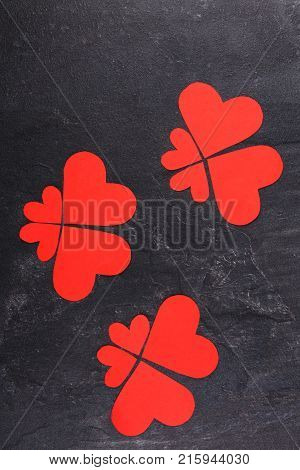 Red hearts carved in different sizes lined up in butterflies close-up on a stone background