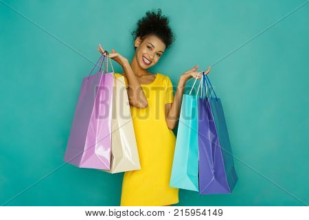 Happy  Girl With Shopping Bags. Excited Smiling Shopaholic Holding Colorful Shopping Bags At Turquoi