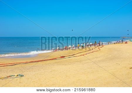 BENTOTA SRI LANKA - DECEMBER 6 2016: The hard work of Sri Lankan fishermen pulling heavy nets from the ocean on December 6 in Bentota.