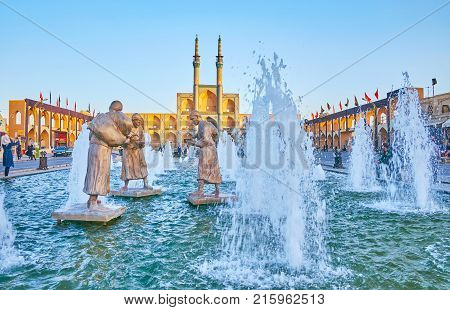 YAZD IRAN - OCTOBER 17 2017: The view on bronze sculptures of water carriers with Amir Chakhmaq complex on the background on October 17 in Yazd