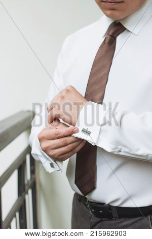 man buttons shirt a man in a white shirt morning groom hands of a man close-up a white shirt on a businessman man buttons shirt sleeve businessman puts on a suit