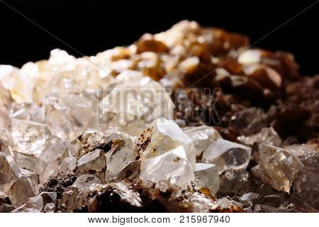 Closeup photograph of white and brown quartz stone lit from above with very small part of black background. Natural phenomenon. Mountain or rock crystal.