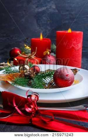 A beautiful Christmas table is decorated with red candles, Christmas trees and red Christmas balls. Side view. Close up.