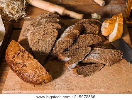 Assortment of different kind of cereal bakery: bread, pasties, buns, pretzel and croissant on old wooden background.