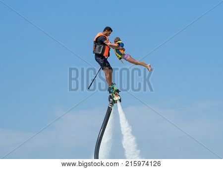 Father and his daughter posing at new flyboard at Caribbean tropical beach. Positive human emotions feelings joy. Funny cute child making vacations and enjoying summer.