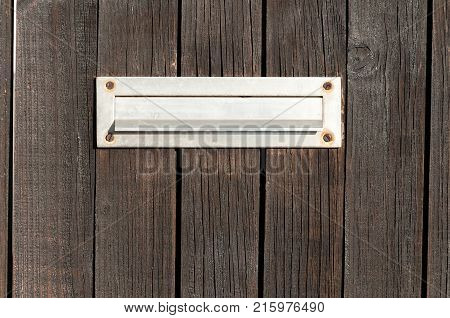Old letterbox or mailbox in the wooden gate door traditional way of delivering letters to the house close up