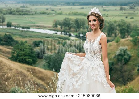 Portrait Of A Young Beautiful Bride On A Background Of A Gorgeous View Of The River And Fields.