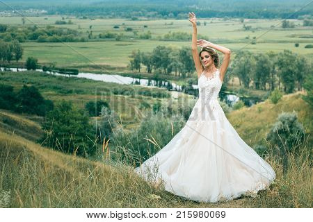 Portrait Of A Young Beautiful Bride On A Background Of A Gorgeous View Of The River And Fields.