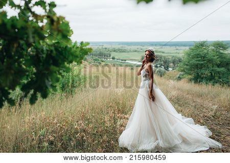 Portrait Of A Young Beautiful Bride On A Background Of A Gorgeous View Of The River And Fields.