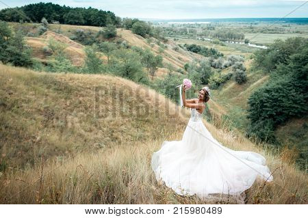 Portrait Of A Young Beautiful Bride On A Background Of A Gorgeous View Of The River And Fields.