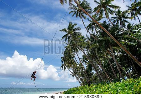 LAVENA FIJI - NOVEMBER 27: Unidentified boy swings on a rope swing on November 27 2013 in Lavena village on Teveuni island Fiji. Taveuni is the third largest island in Fiji.