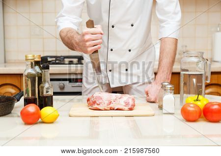 Butcher cutting meat on chopping board, professional cook holding knife and cutting meat