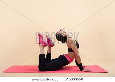 A Young Attractive Girl With A Ponytail, A Brunette, Is Lies In A Cobra Pose With Knees Bent, Doing 