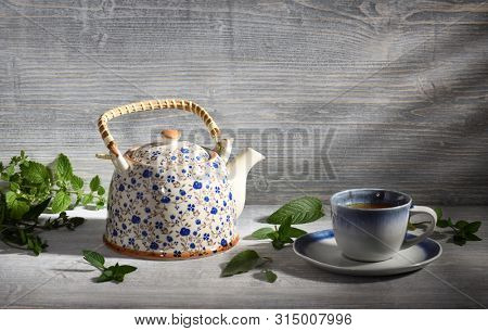 teapot and cup of herbal tea with nerbs