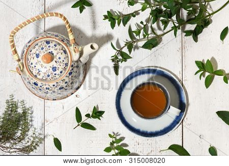 teapot and cup of herbal tea with nerbs