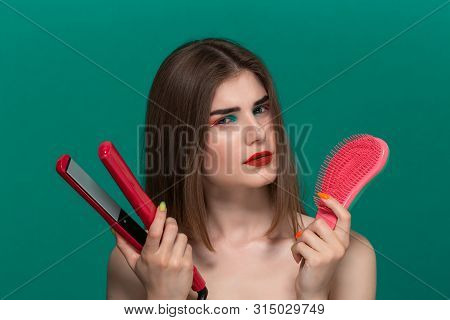 Portrait Of A Thoughtful Beautiful Young Woman With Bright Color Make-up Doing Hair Style Herself Wi