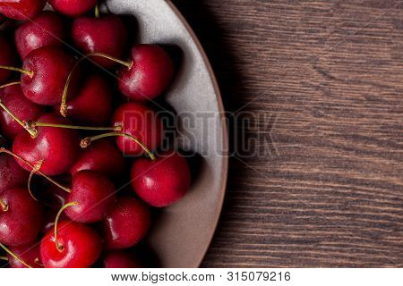 Cherries On A Plate, On A Wooden Background. Summer Picnic, Harvest, Treats. Food For Vegetarians An