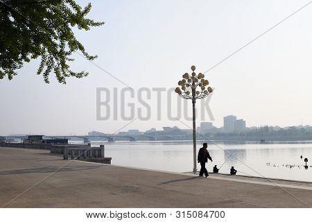 Pyongyang, North Korea - May 1, 2019: Locals Fishermen Catch A Fish On Waterfront On Kim Il Sung Squ