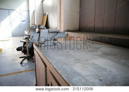 Shallow Depth Of Field Image With A Rusty And Dirty Heavy Iron Vice On A Workbench Inside A Workshop