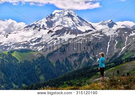 Sporty Woman Relaxing In Alpine Meadows And Enjoing Scenic View Of Volcano Covered With  Glaciers An