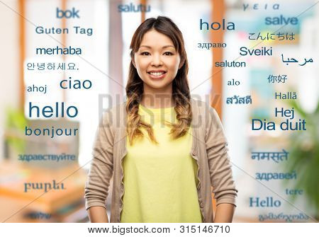 education, communication and translation concept - happy asian young woman over greeting words in different foreign languages