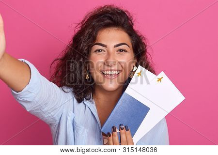 Travel And Lifestyle Concept. Young Happy Female Traveller With Curly Air Holding Passport With Flig