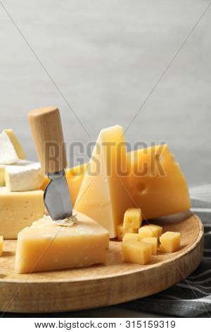 Different Types Of Delicious Cheese In Wooden Plate Against Light Background