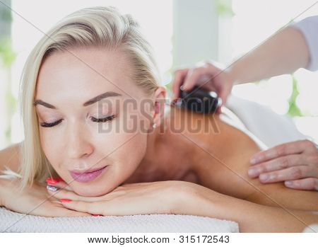 Young Woman In Spa Salon, Getting Stones Massage