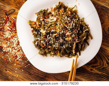 Seaweed Salad With Sesame Seeds Is On A White Plate