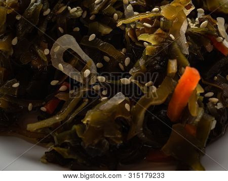 Seaweed Salad With Sesame Seeds Is On A White Plate